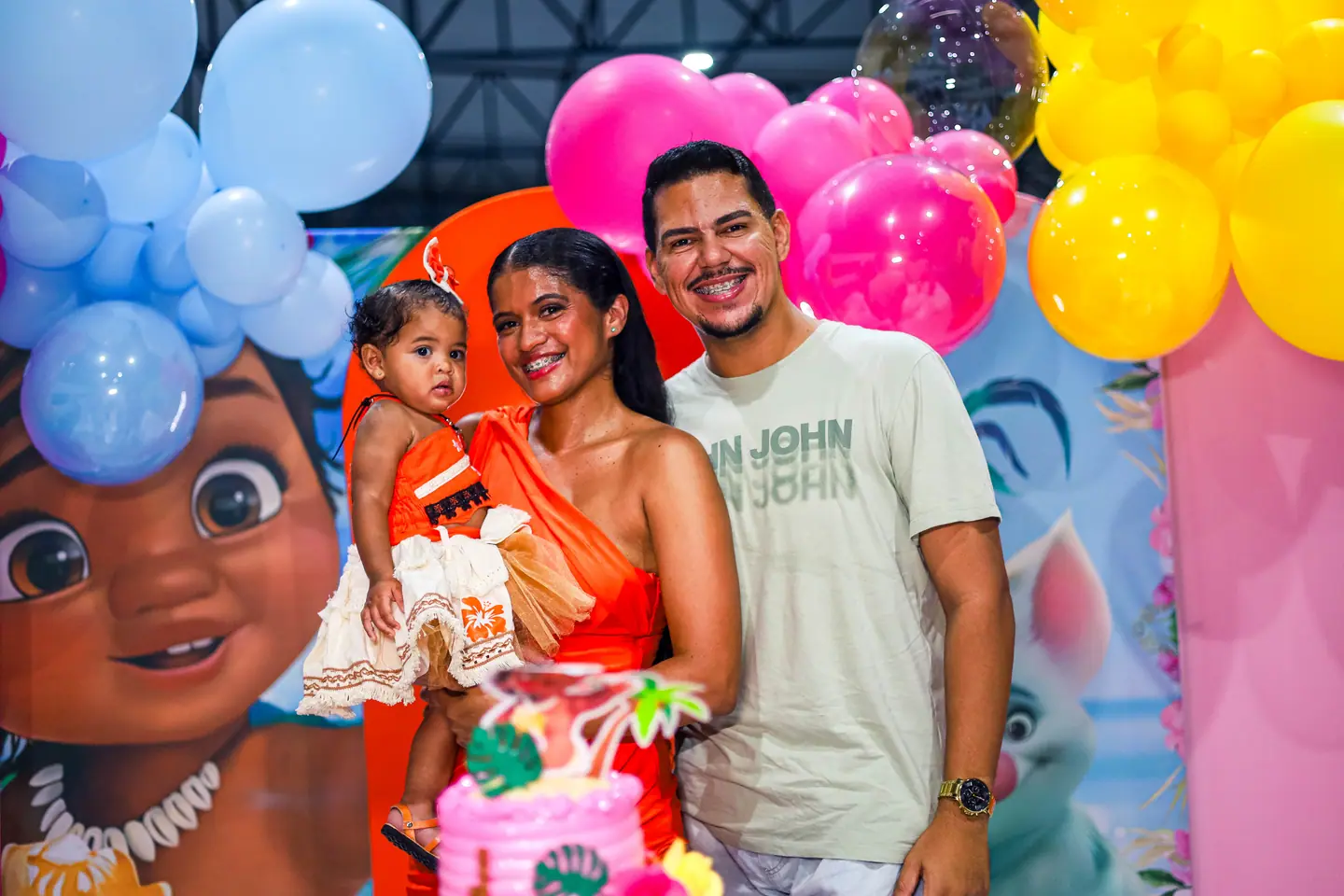 Família posa com a aniversariante diante do painel de balões da Moana