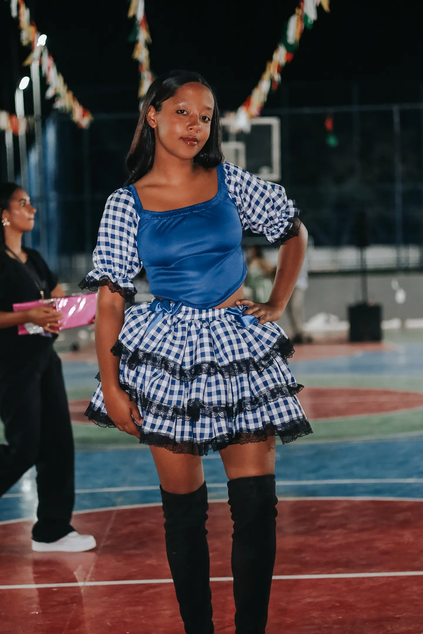 Dançarina de quadrilha com vestido xadrez azul posa na quadra