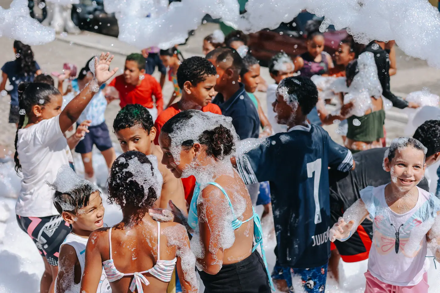 Crianças brincam na festa da espuma em praça pública