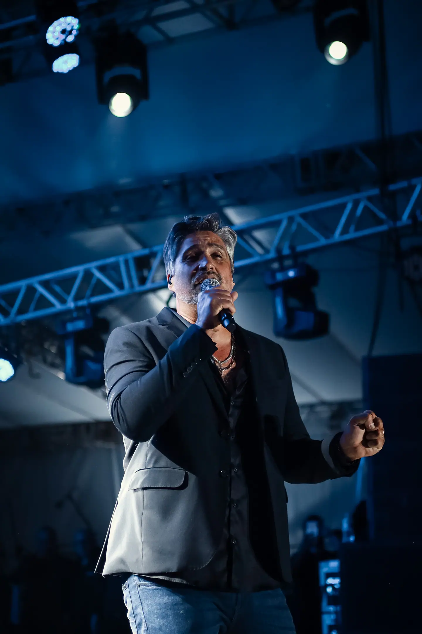 Cantor de blazer canta sob treliça iluminada em azul